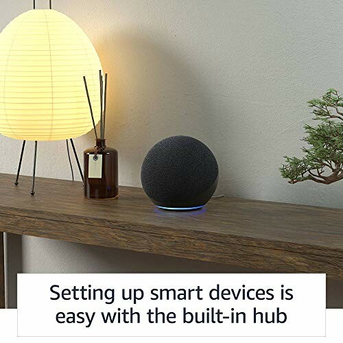 Smart speaker on a table next to a lamp and plant.